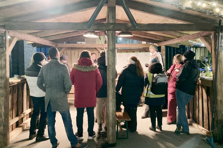 Mitarbeitende aus dem Gewerbegebiet stehen zusammen in kleiner Adventshütte