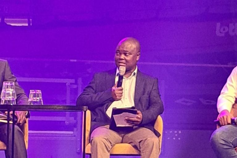 Brian Zvomuya aus Harare spricht auf einer Bühne in ein Mikrofon