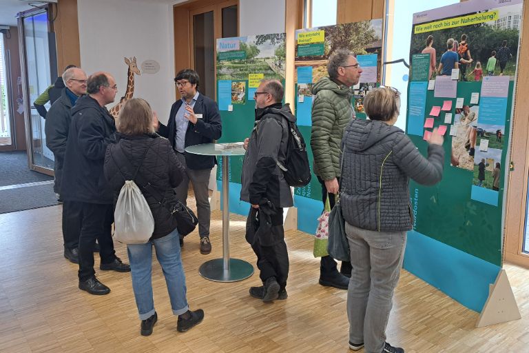 Menschen vor Infotafeln sprechen miteinander