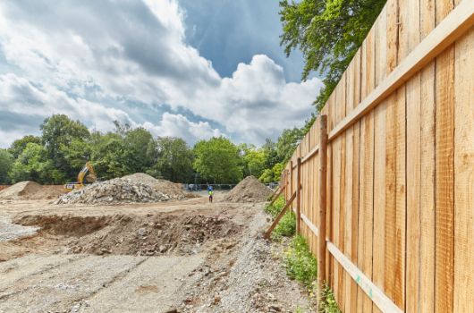 Ein hölzerner Bauzaun umschließt das Baugrundstück