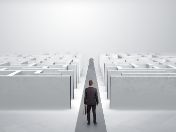 Mann mit Aktentasche steht vor einem Labyrinth, aber vor ihm tut sich ein gerader Weg auf