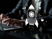 Rakete (Grafik) vor einer Person am Computer