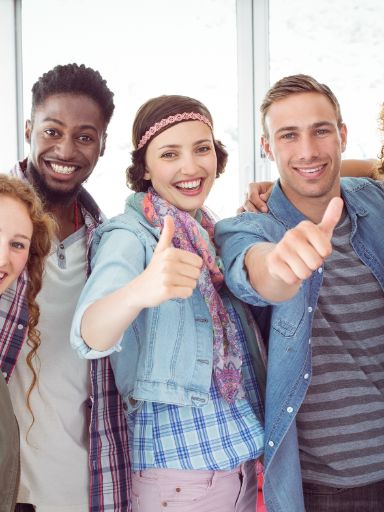 Studenten lächeln mit Daumen nach oben in die Kamera