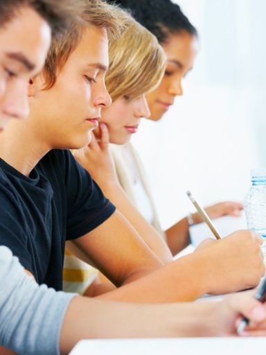 Mehrere Schüler in einer Reihe, die aufmerksam zuhören oder mitschreiben