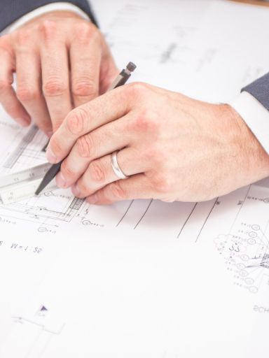 Mann zeichnet technsichen Plan.